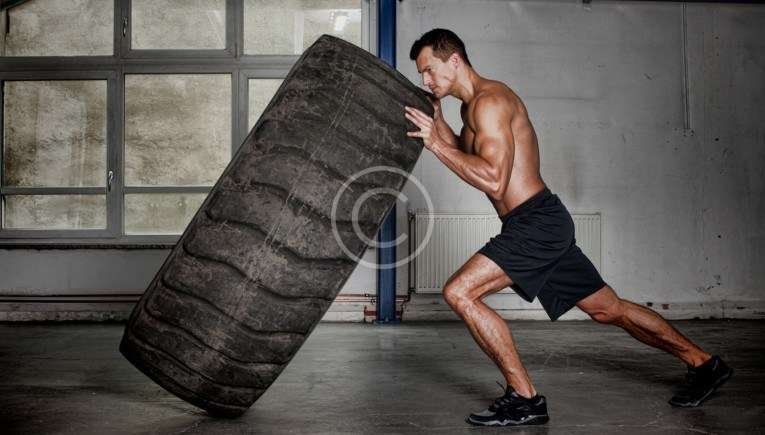 man doing intense crossfit tire flipping training