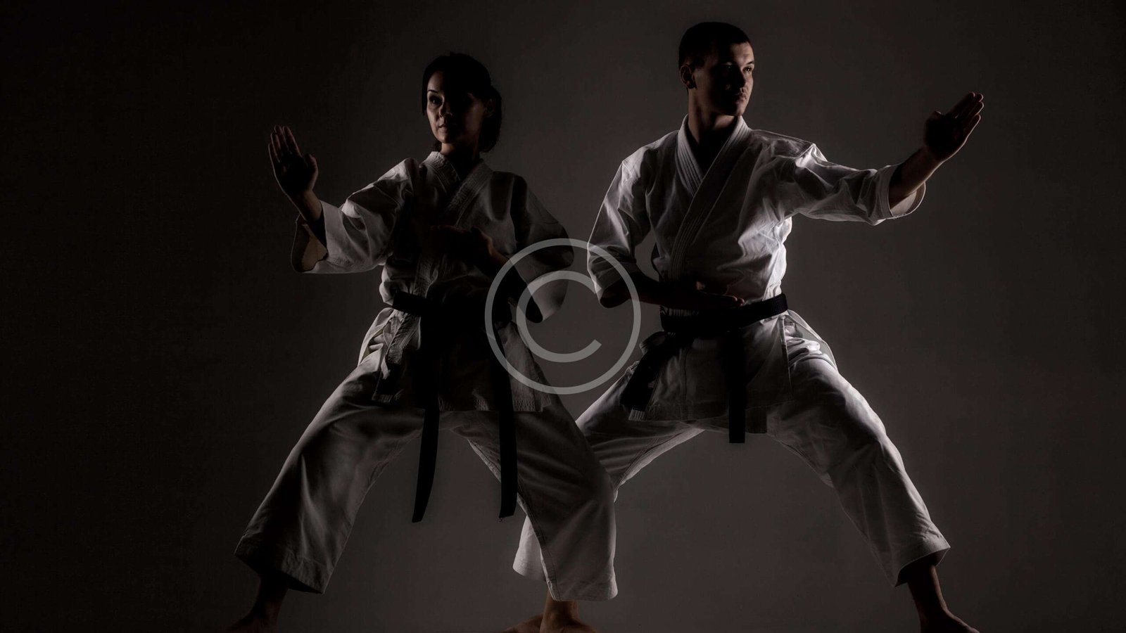 karate girl and boy posing against dark background